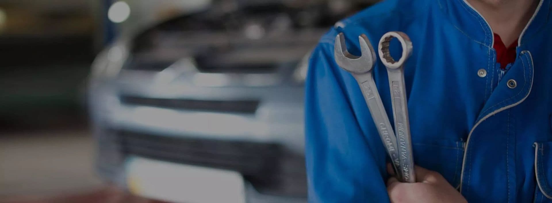 Mechaniker mit Maul- und Ringschlüssel vor einem Citroën in der Werkstatt